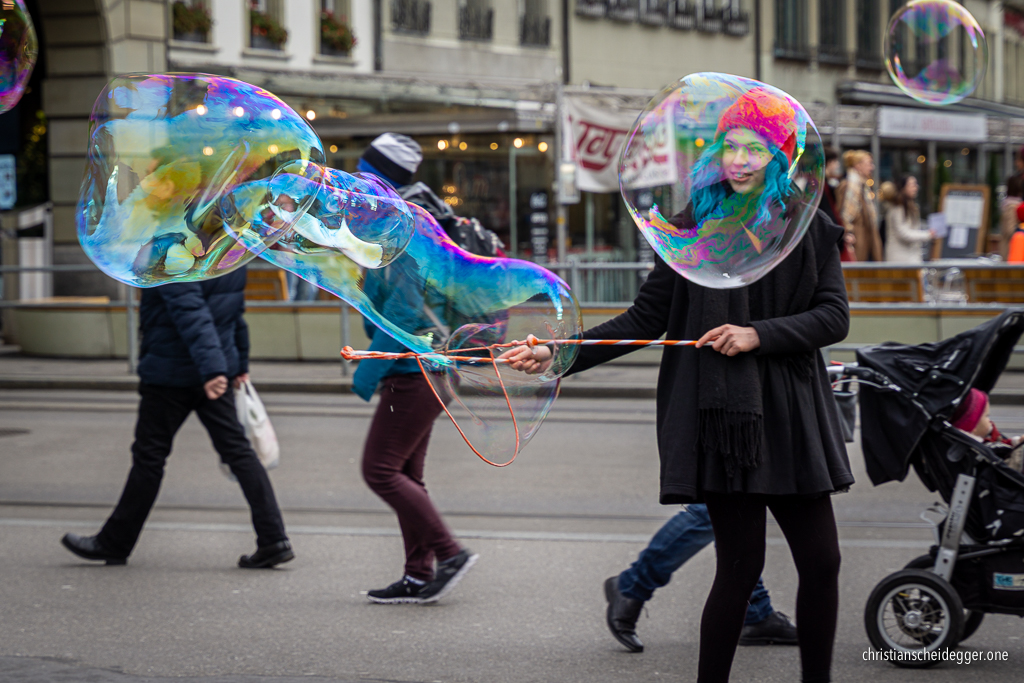 Mädchen und Passanten hinter grossen Seifenblasen